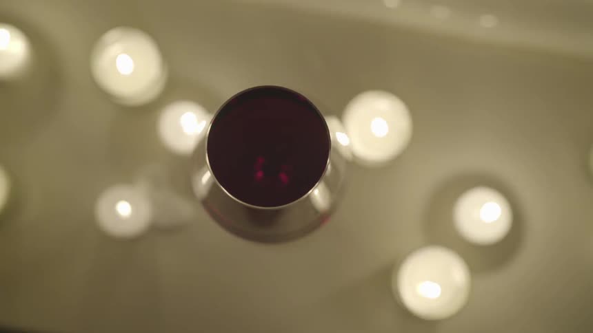 A metal bowl with red material inside of it towers over burning tea candles