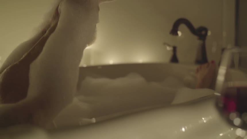 Woman in bubble bath raises leg out of water