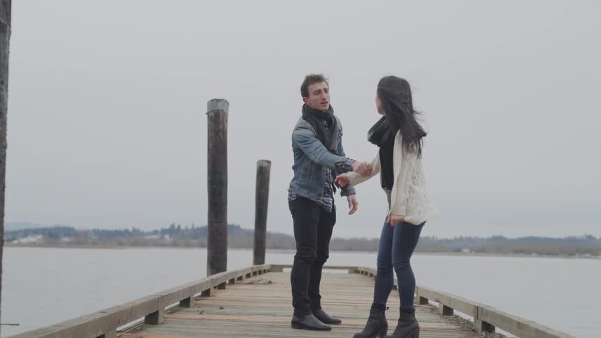Asian woman and white man argues on wooden pier and the woman slaps the white man across the face on a cloudy day