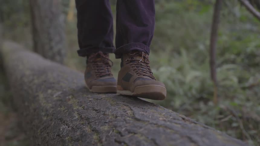 Someone walks carefully across a fallen log