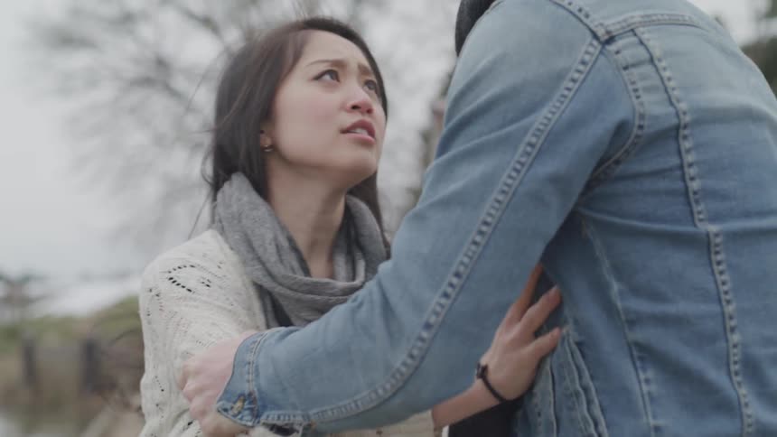 A man angrily grabbing at a woman who is trying to pull away