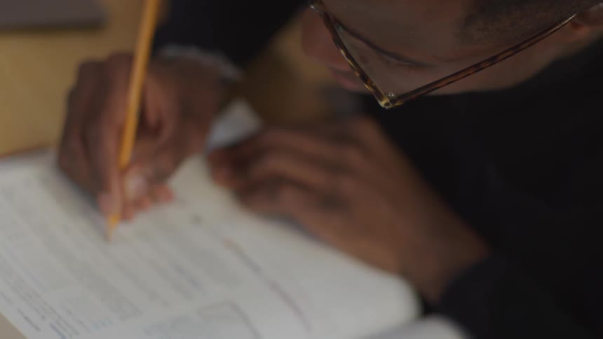 A student sitting at a desk completes a worksheet using a pencil