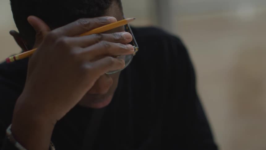 A student fidgets with his pencil as he looks down studying and reading