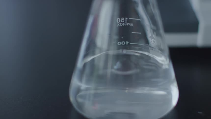 Close up shot of liquid dripping into a beaker