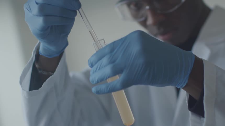 Black man fills a pipette with a liquid from a test tube