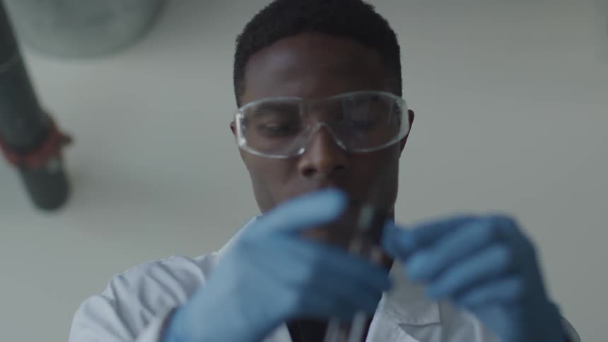 Scientist observing red liquid from a test tube as it moves towards bottom