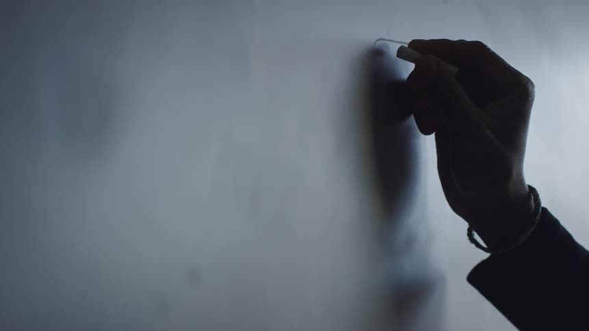 A man draws a picture on a chalkboard