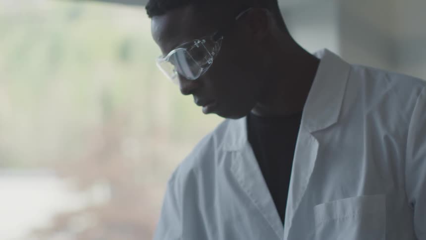 A white in a lab coat at protective goggles observes something