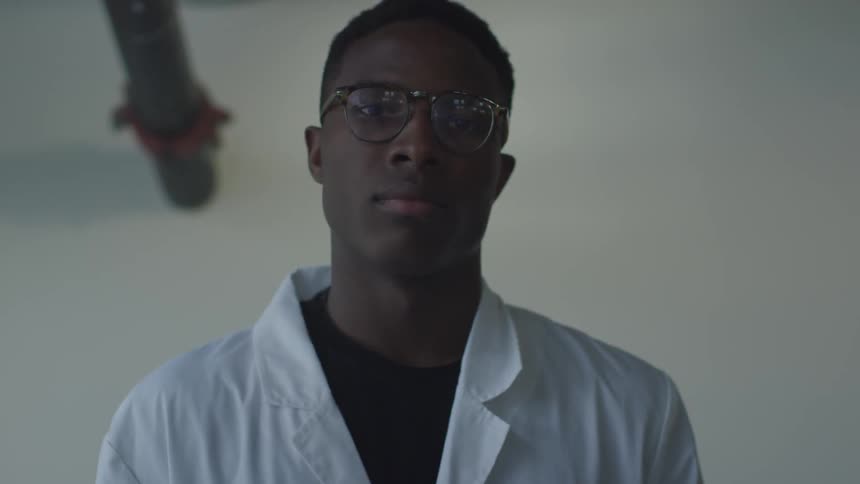 A man turns forward wearing a lab coat