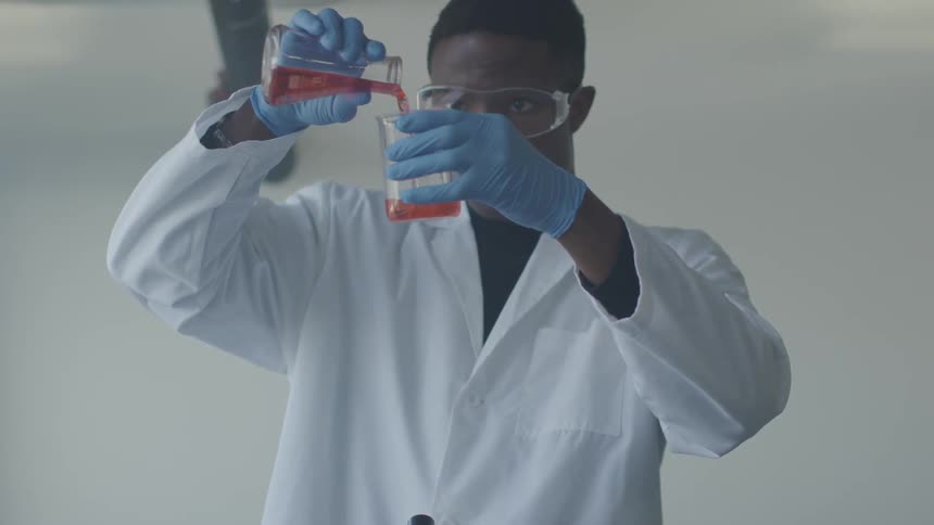 A man is pouring liquid into a beaker