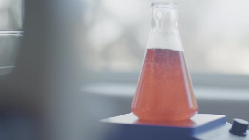 A flask on a desk is being boiled by an instrument inside at day