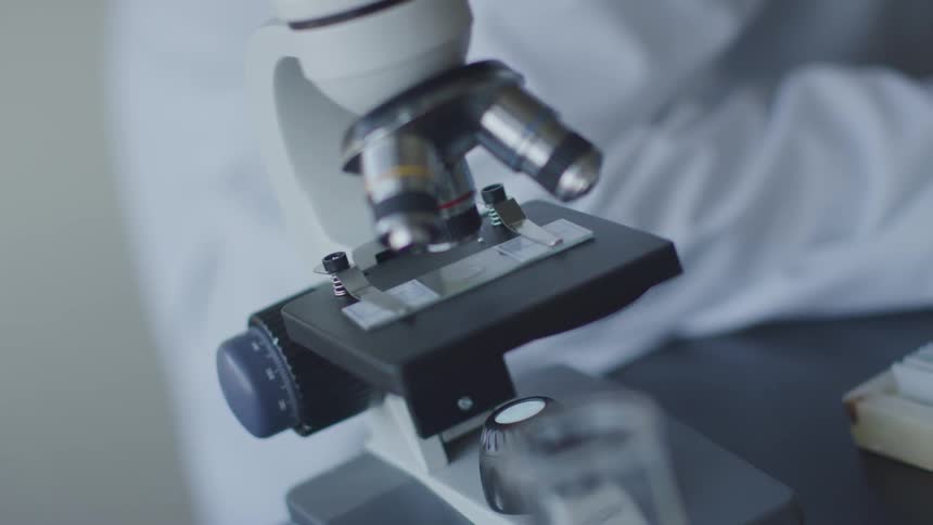A microscope on a table next to a person
