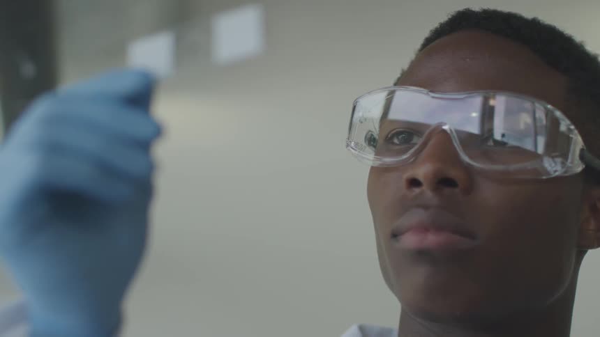 A scientist wearing safety glasses puts down a slide he has been examining