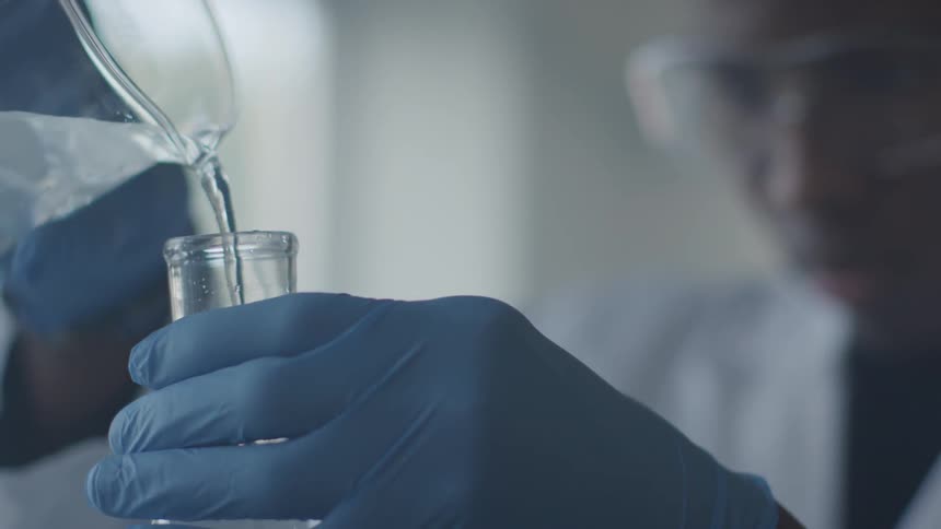 Man pours liquid from beaker into test tube