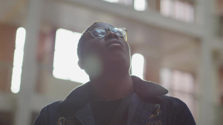 Man wearing glasses looks up towards the sky as he smiles