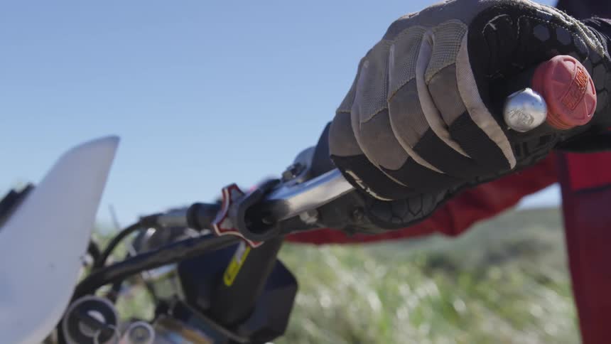 A person is sitting on a motorcycle squeezing the brake lever
