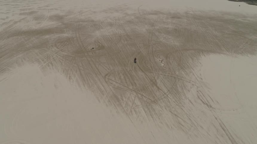 A man riding a bike through the desert sand