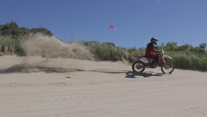 A person rides a dirt bike in the sand