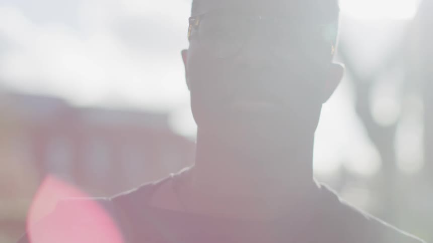 A man is standing under the bright sun