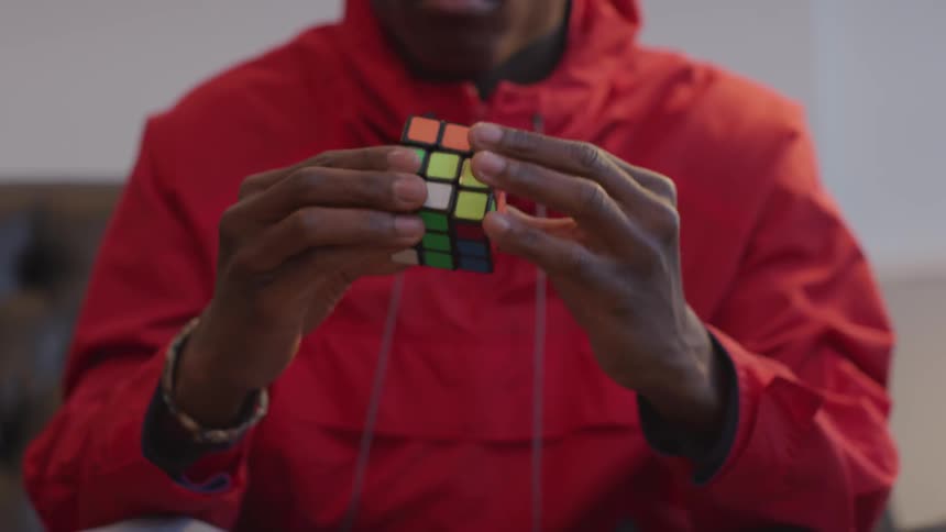 Black man works on a Rubik's cube