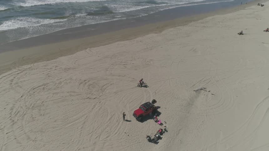 A person rides a motorcycle on a beach
