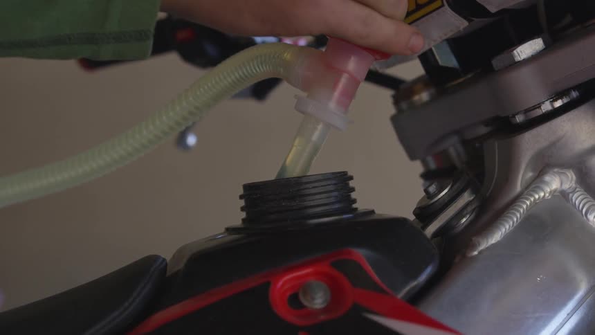 A person adds fuel to a motorcycle