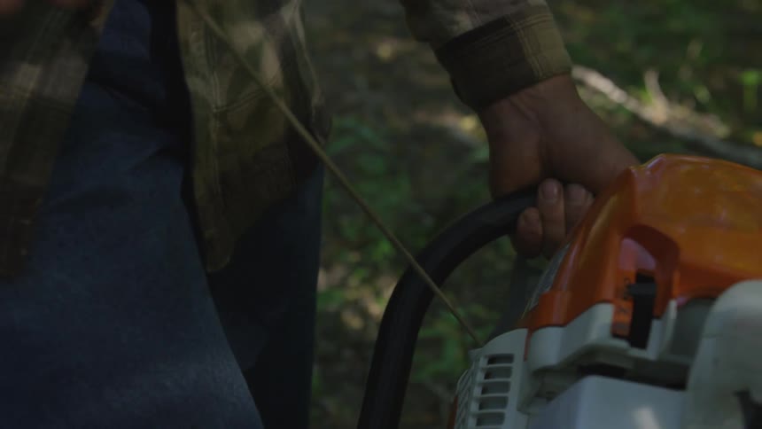 A man pull starting a chainsaw