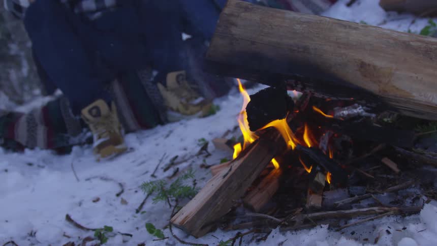 People sit around a fire in the snow
