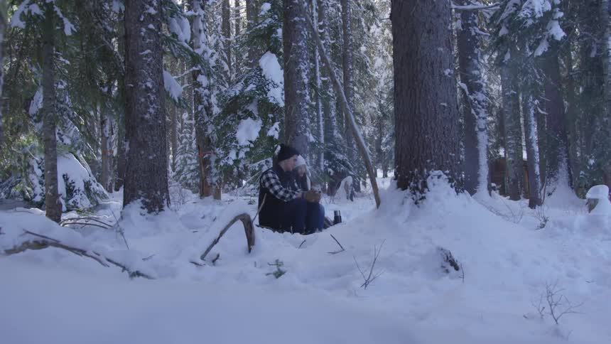 A man and woman sitting together in the snowy forest