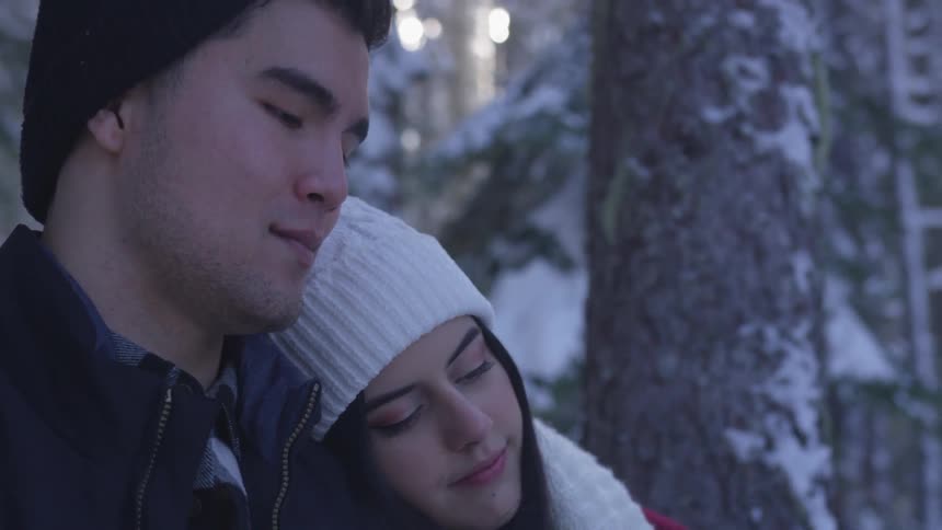 A woman leaning against a man in a forest