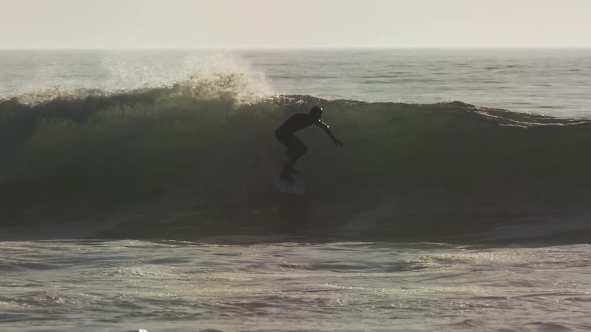 A surfer is riding waves, but then jumps and falls into the wave