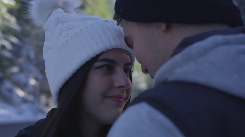 A man and woman close to kissing each other while standing in the snow