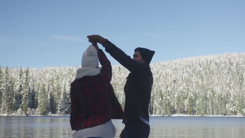Couple dancing at the shore of a lake at winter