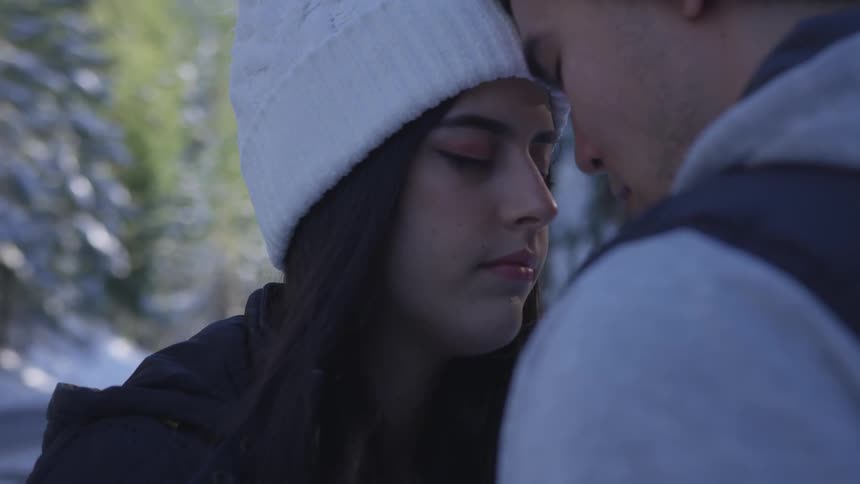 A man and woman rest their foreheads together outside on a winter day