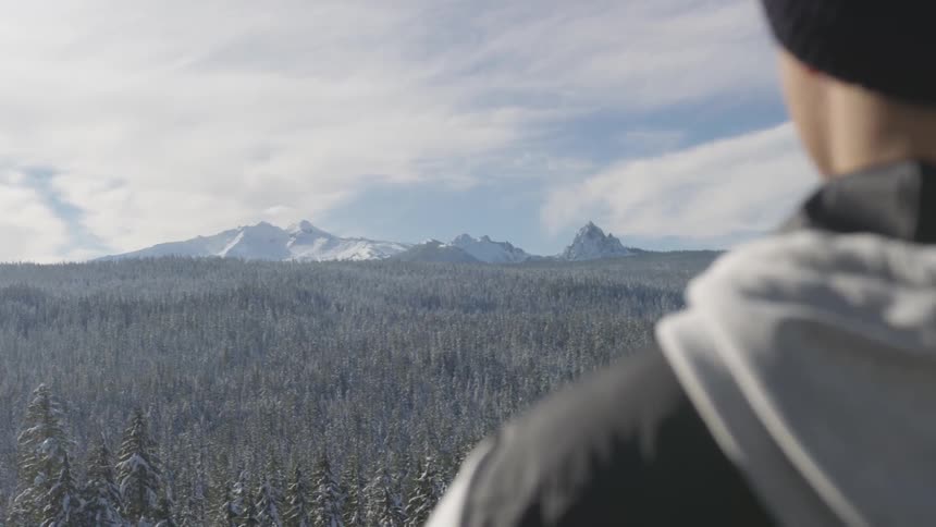 A man stares into the distance at the mountains