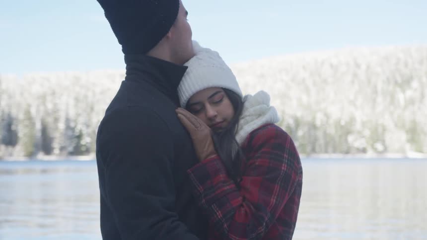 A man and woman hug beside a river
