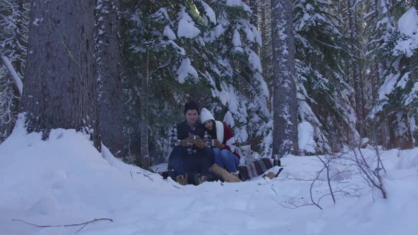 A man and woman sitting in the snow
