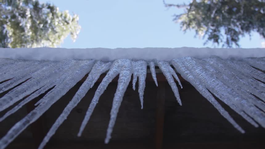 Icicles formed off of the roof of a structure under a clear blue sky