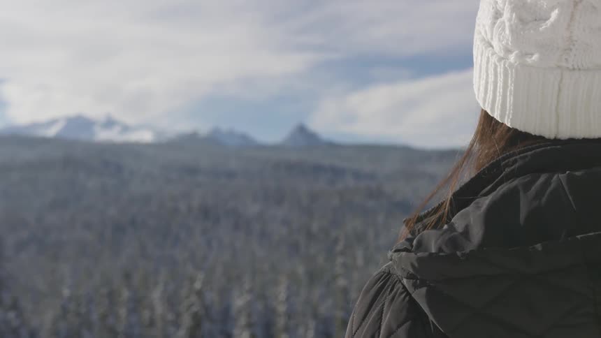 A woman is on a hill looking out over the wilderness