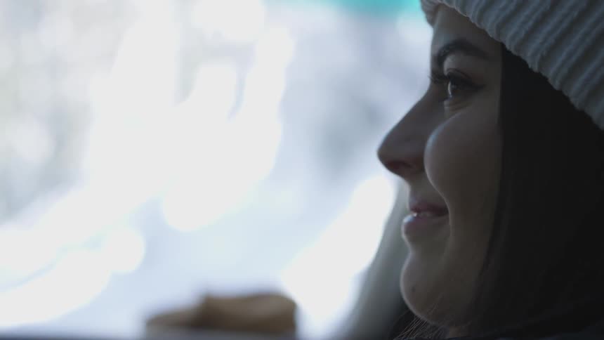 A woman smiles as she looks out the window in a moving vehicle
