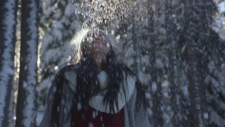 Young woman throws a handful of snow over her head