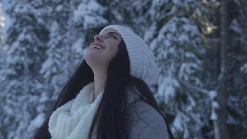 A woman looks around at snow covered trees