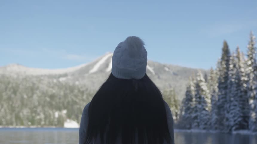 Woman looking at a mountain from the shores of a lake