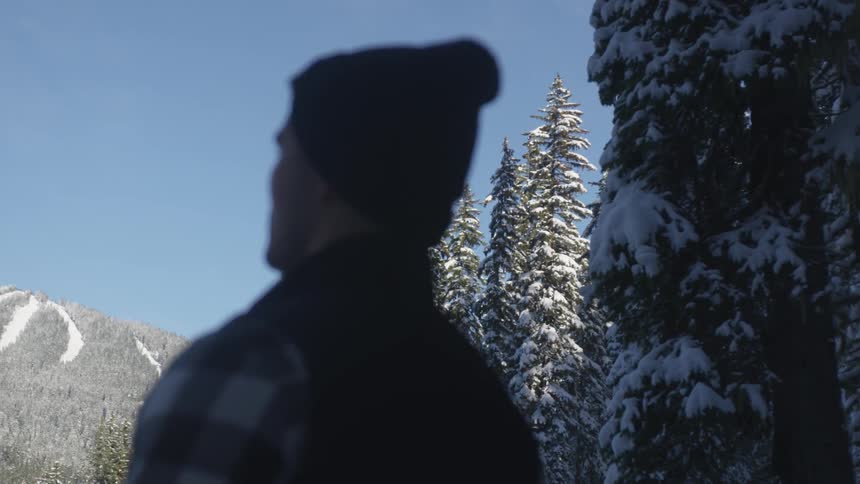 A man is standing in the wilderness looking towards a mountain