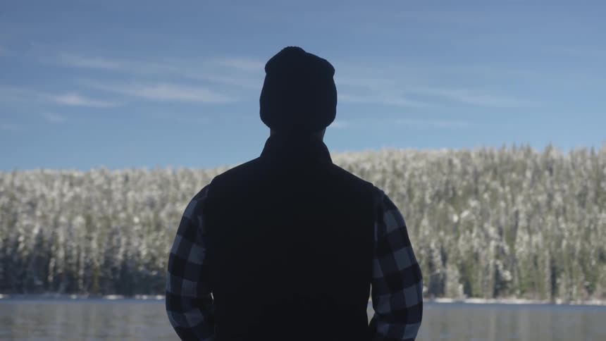 Silhouette of a male looking at the lake in the mountains