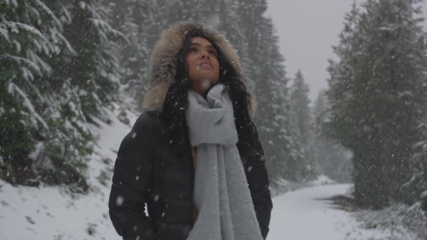 A woman stands on a forest road in the snow