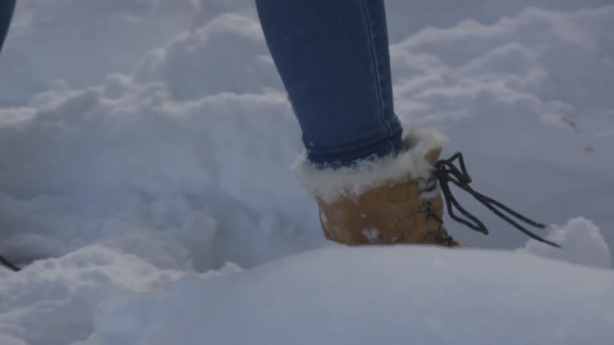 A woman wearing boots walks through the snow