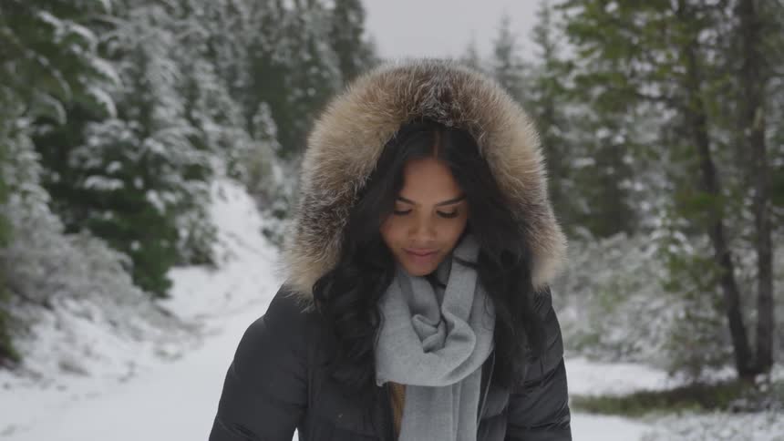 A woman wearing a fur lined coat standing on a roadway