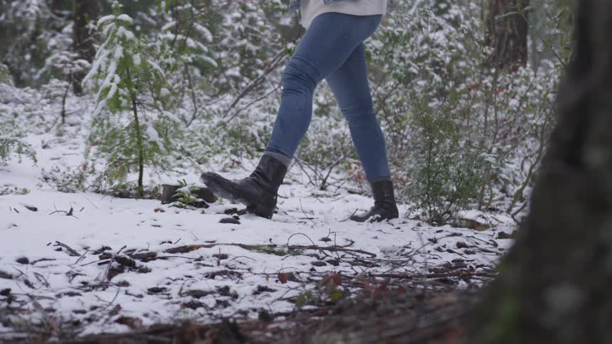 A woman wearing boots walking through the snow covered ground
