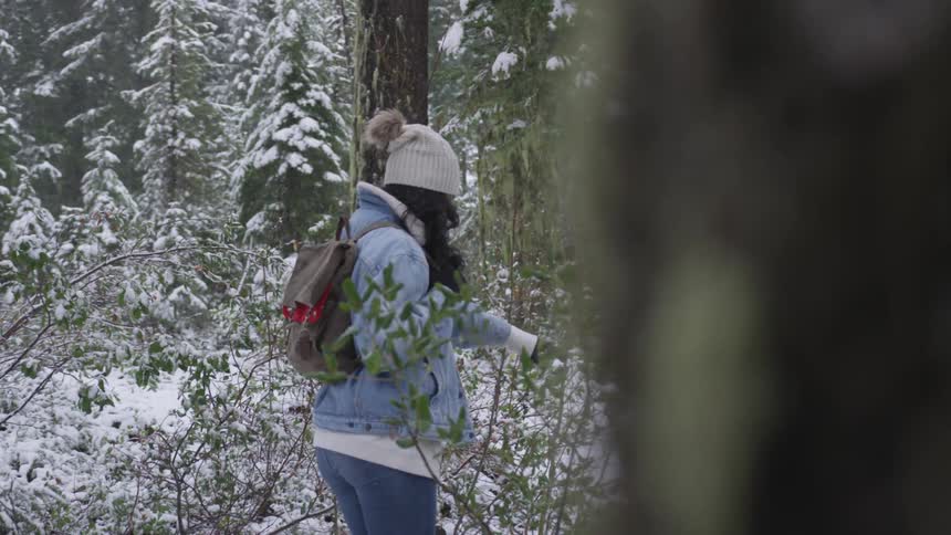 A woman is hiking in the snow covered woods